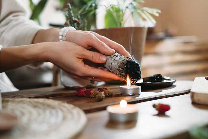 Woman's hands lighting a sage smudge stick on a candle